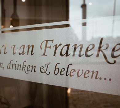 Eten drinken en beleven... slogan van Poort van Franeker op raam hotel-restaurant in Franeker. En op zoek naar een gastvrouw of gastheer.